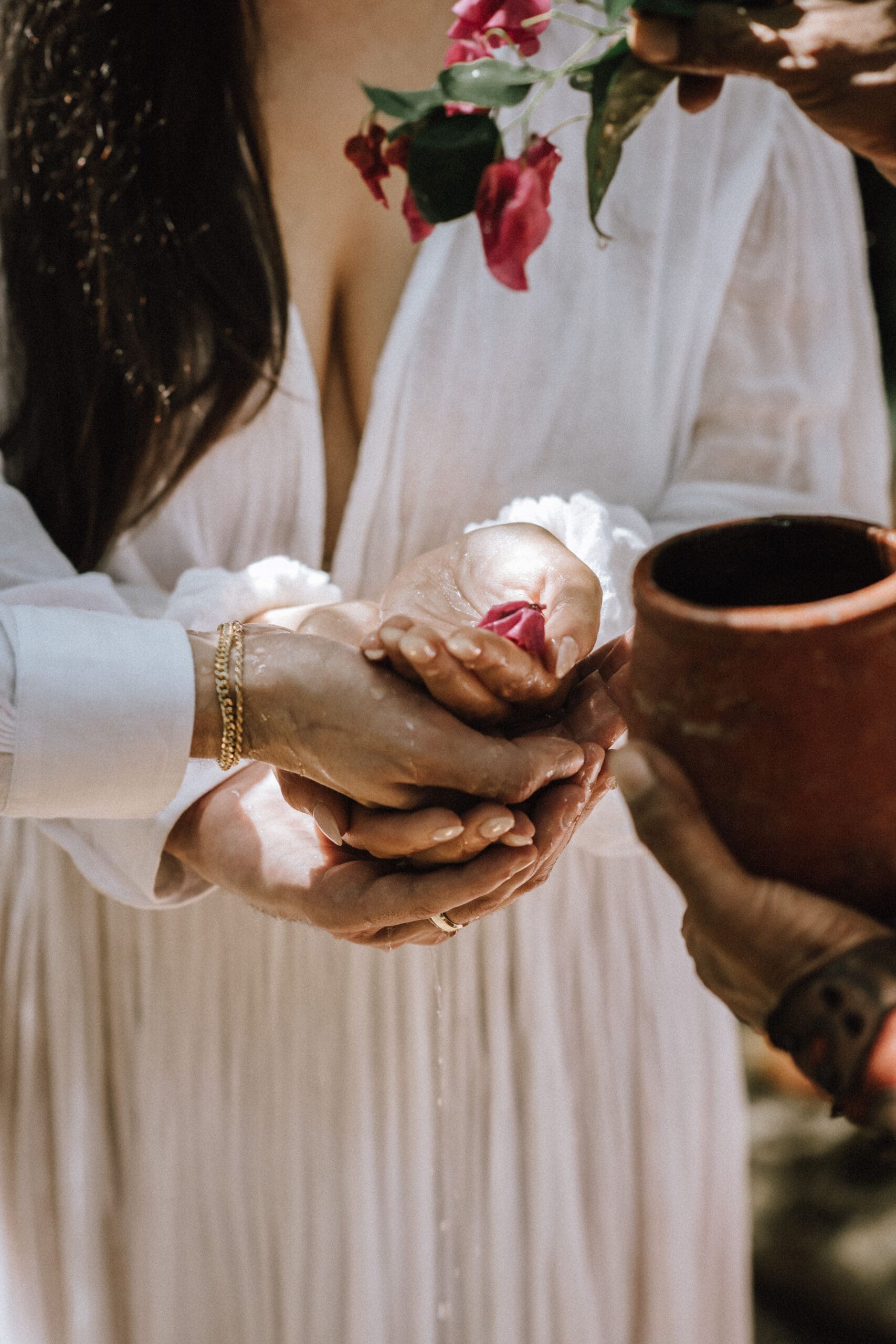 Blessings with petals and water as a couple elopes at a cenote in Tulum Mexico during their Mayan ceremony.