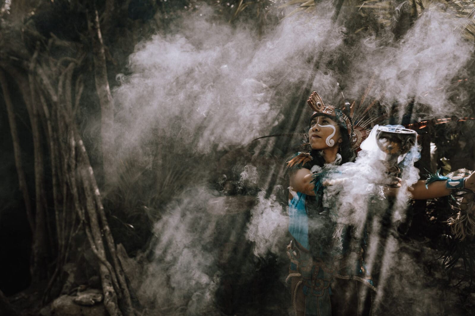 Mayan medicine woman using copal to cleanse the energy while beams of light and smoke cut through the jungle canopy at an elopement in Tulum.