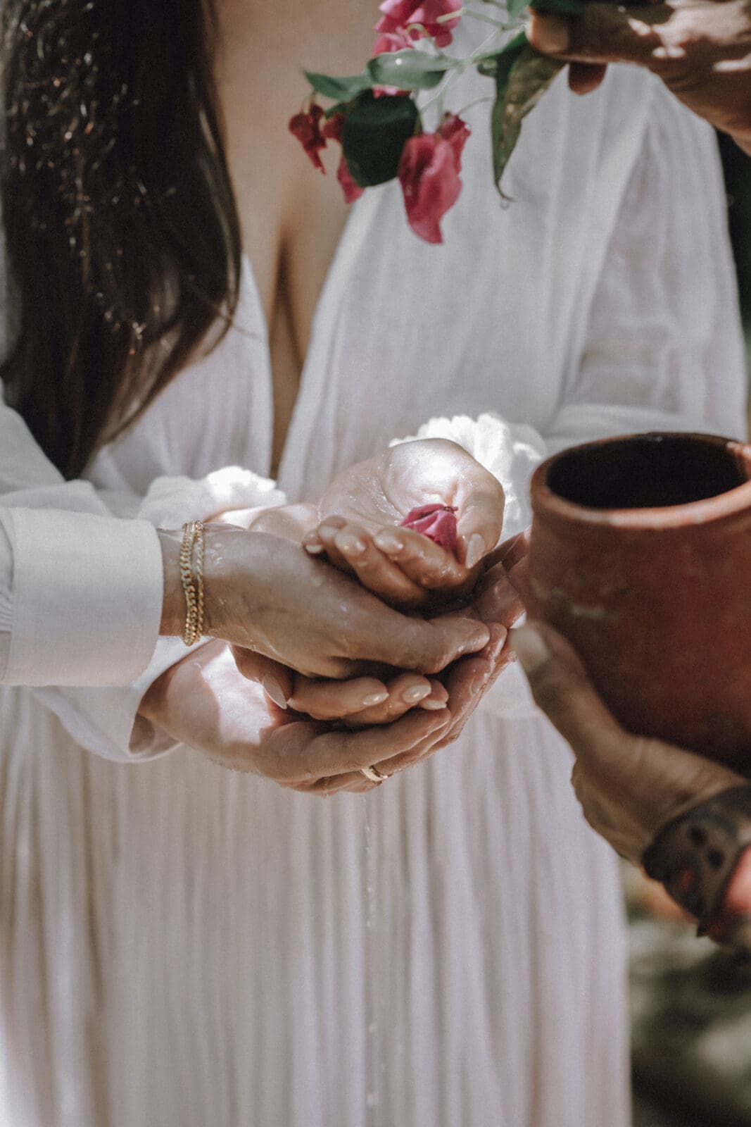 Water and Petals are showered over a couple as a blessing during their holistic spiritual elopement at a cenote in Tulum.
