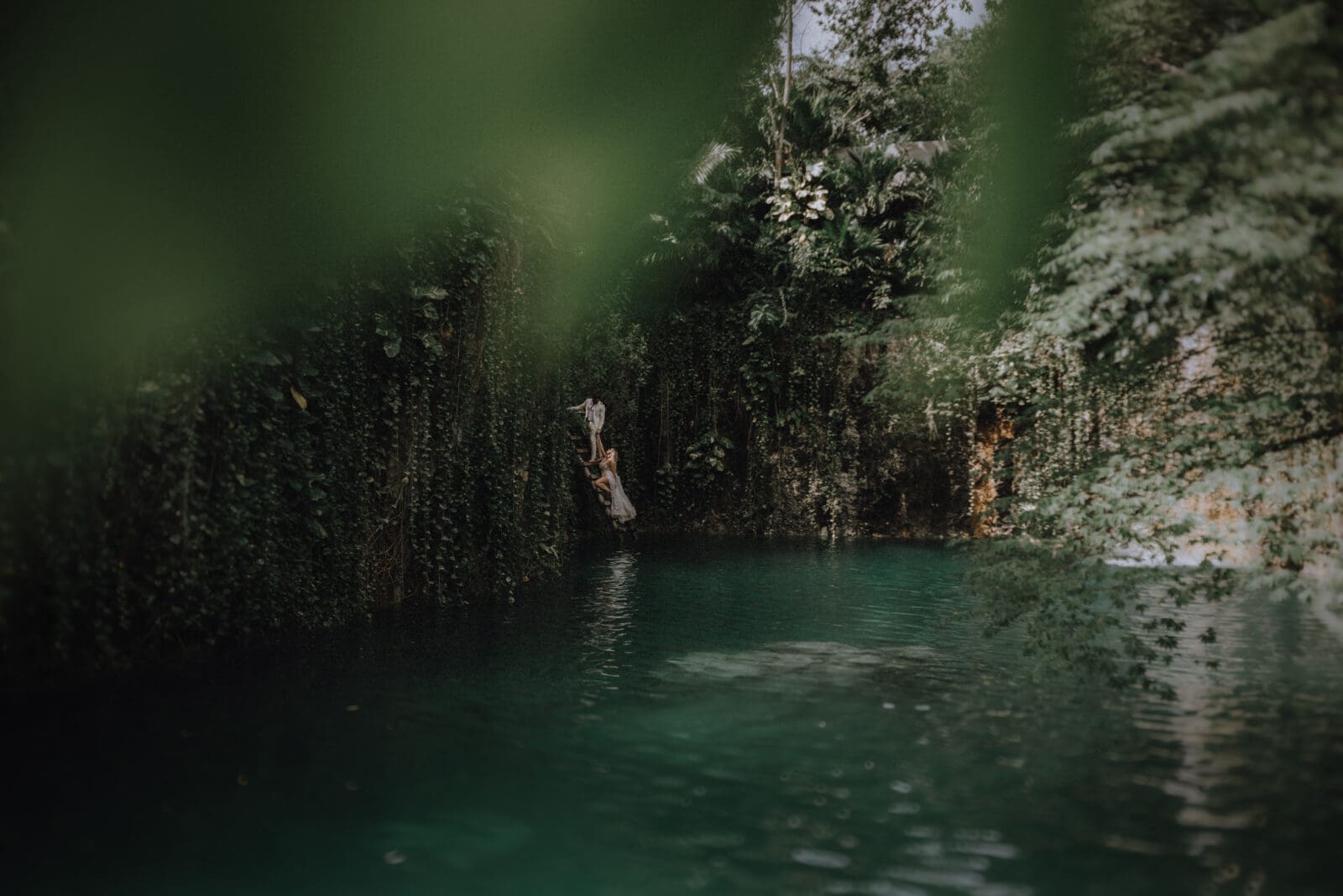 Intimate cenote elopement at Atik Tulum with couple climbing out of the cenote, hand in hand, surrounded by sacred jungle.