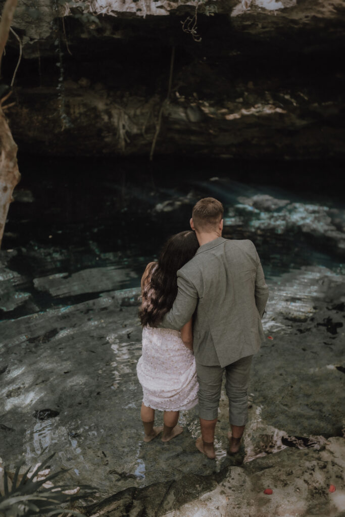 After their Mayan elopement ceremony the bride and groom stand in the refreshing water of the cenote in Tulum.