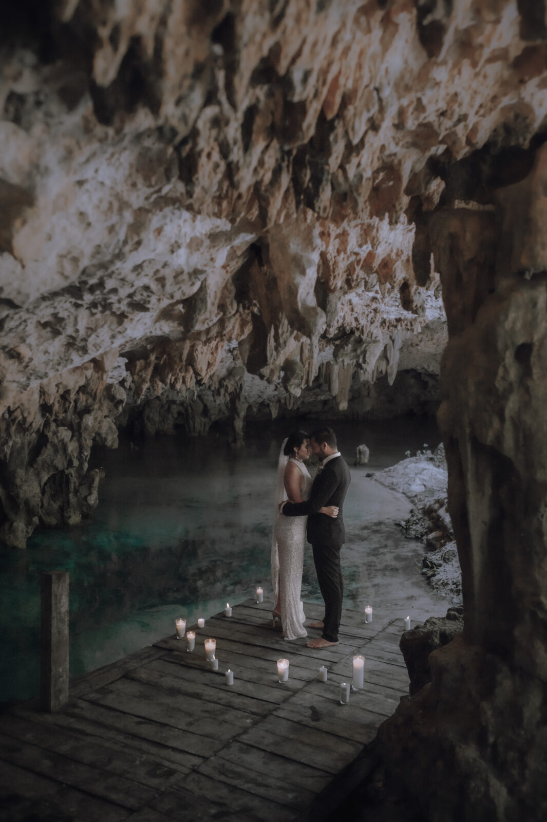 A couple is surrounded by candles while embracing during a Cave Cenote Elopement in Tulum